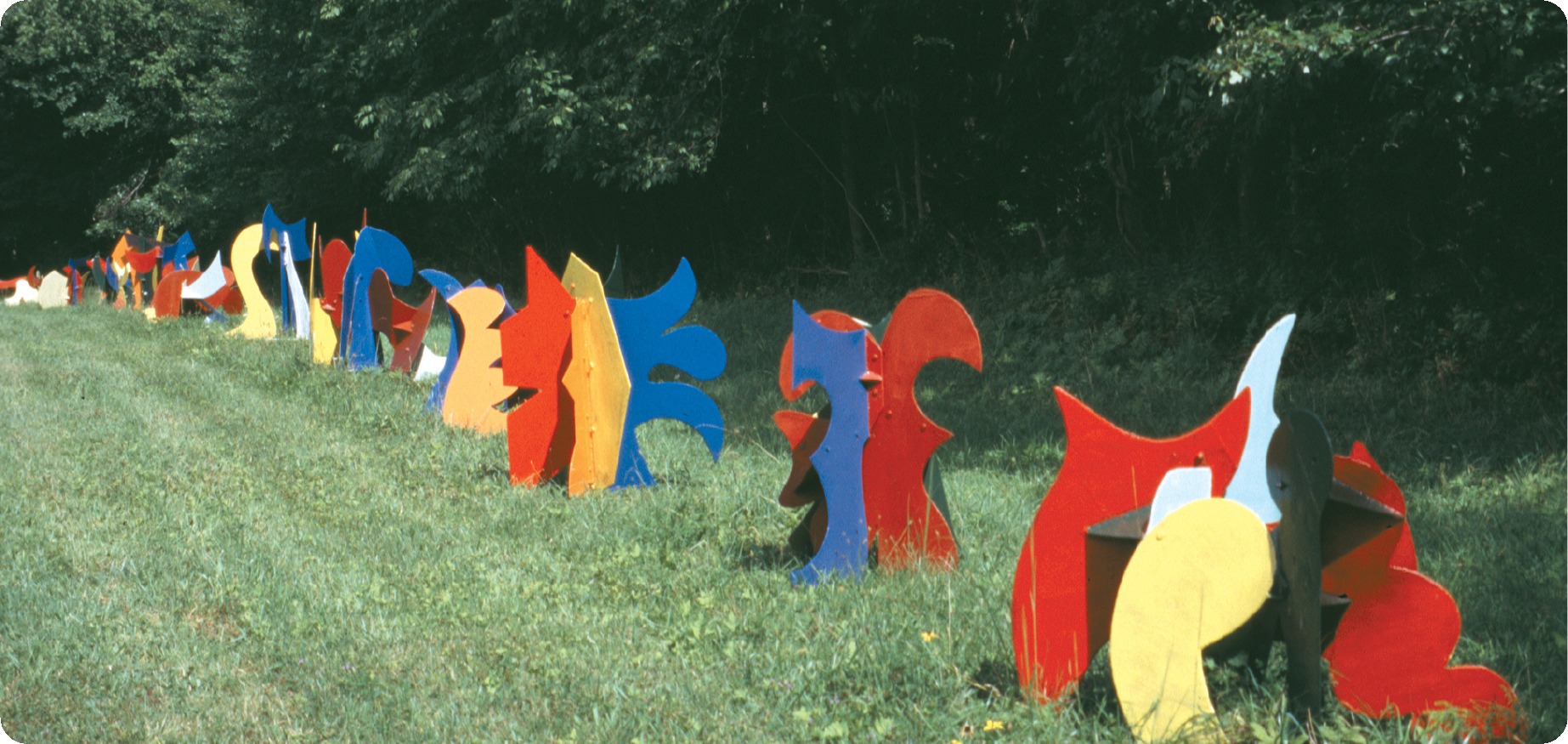 A long line of colorful David Hayes sculptures installed across a field
